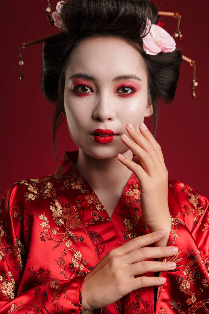 Immagine di affascinante donna geisha nel tradizionale kimono giapponese che danza isolata su sfondo rosso
 - Foto, immagini