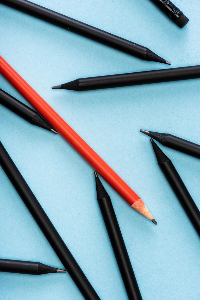 Top kilátás egyedülálló piros ceruza között fekete kék háttér - Fotó, kép