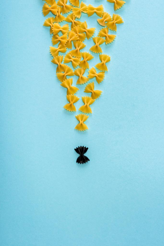 Draufsicht auf einzigartige schwarze Pasta zwischen gelb auf blauem Hintergrund - Foto, Bild