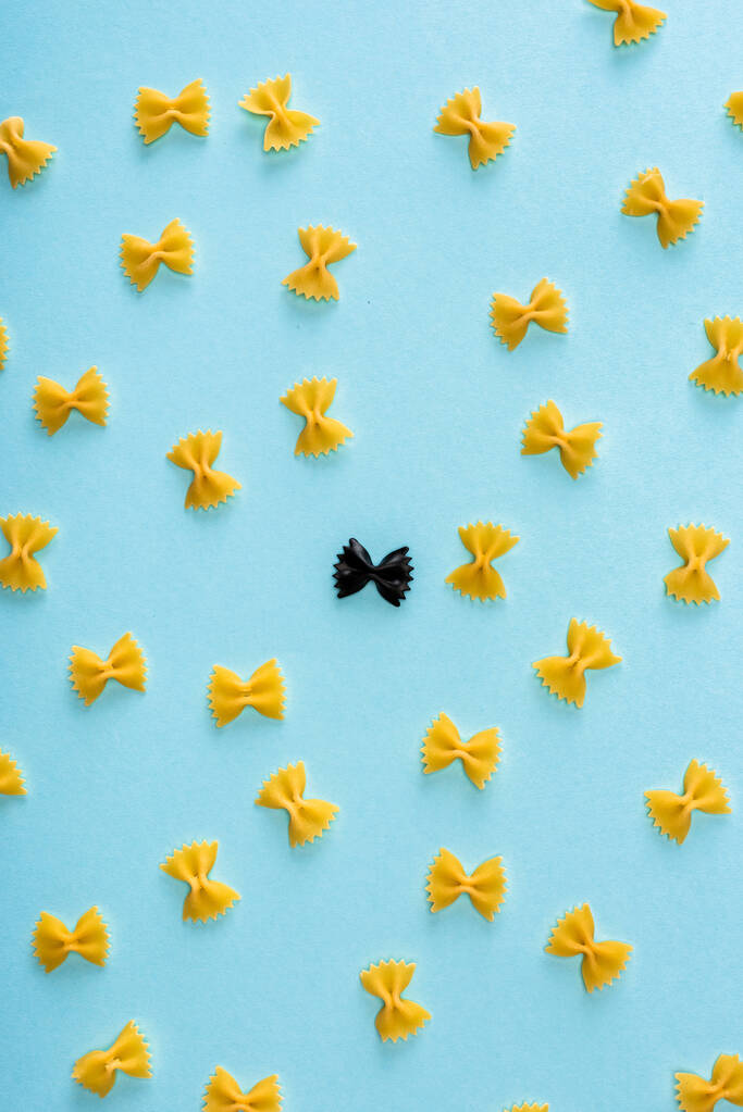 Płaska leżanka z unikalnym czarnym makaronem wśród żółtych na niebiesko  - Zdjęcie, obraz