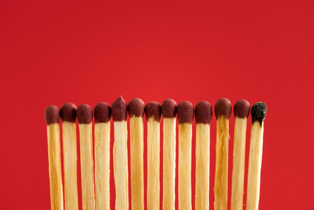 Burned match among another isolated on red - Photo, Image
