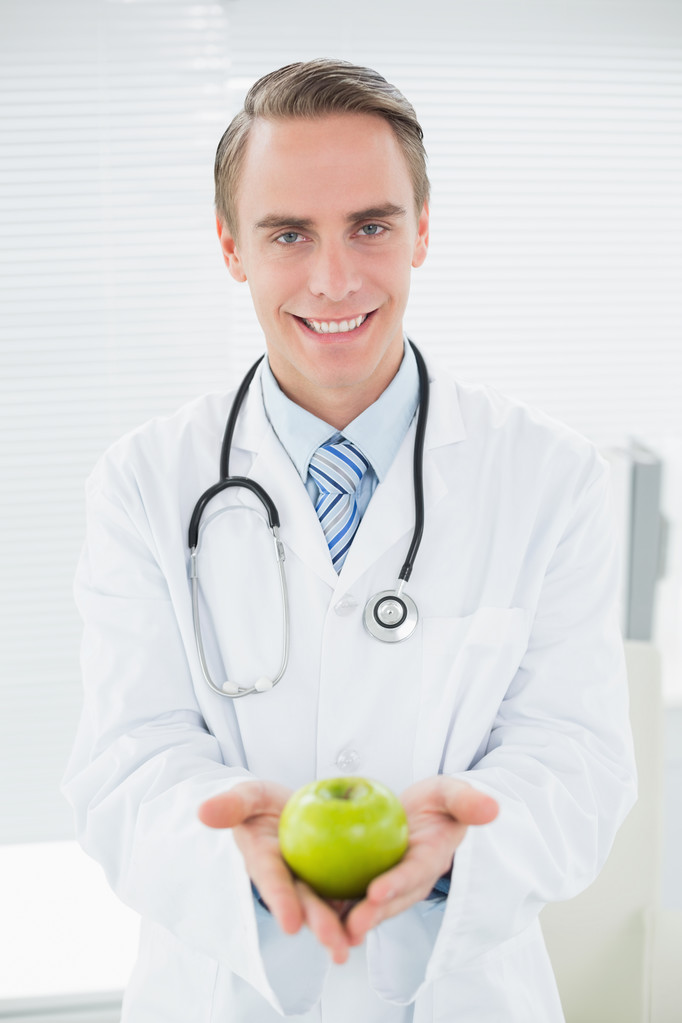 Усміхнений чоловік лікар тримає зелене яблуко
 - Фото, зображення