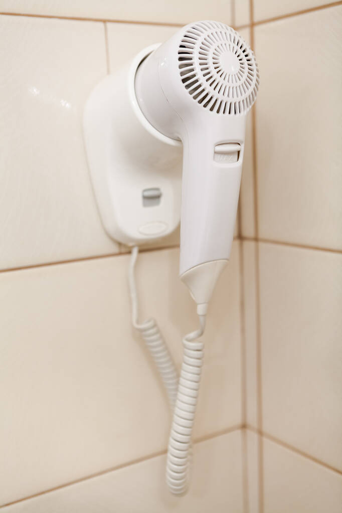 Bílý vysoušeč vlasů visí na zdi v koupelně - Fotografie, Obrázek