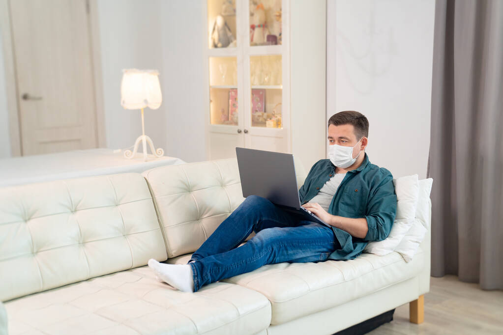freelancer en máscara médica trabajando en sofá
 - Foto, imagen