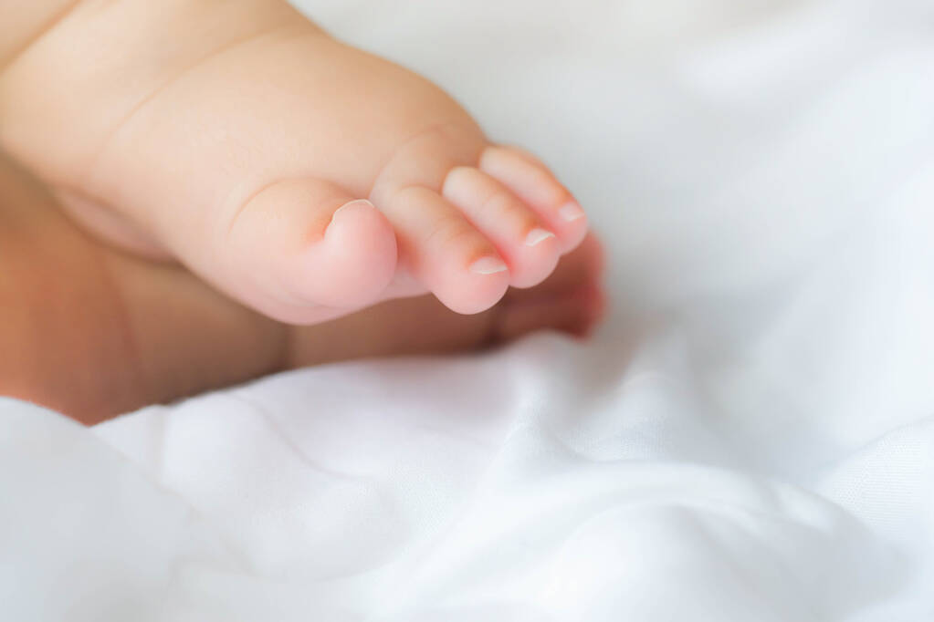 Portré egy újszülött ázsiai kisfiú aludni az ágyon, aranyos szelektív kéz láb lábujjak - Fotó, kép