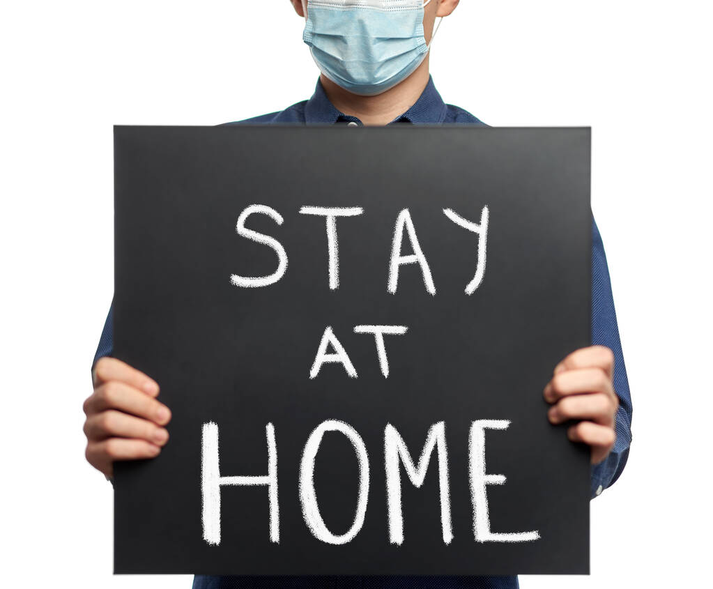 Muž s obličejovou maskou a tabulí se zprávou # zůstaň doma - Fotografie, Obrázek