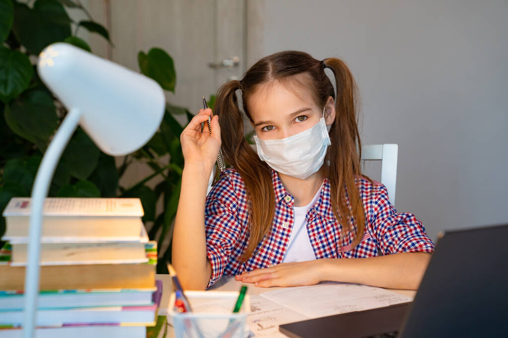 teen dívka v lékařské masce naslouchá lekci na notebooku  - Fotografie, Obrázek