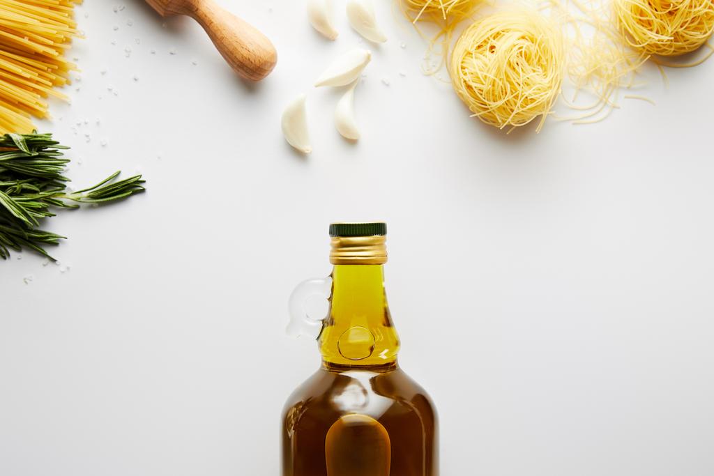 Vista dall'alto di bottiglia di olio d'oliva, mattarello, pasta, aglio e rosmarino su fondo bianco
  - Foto, immagini