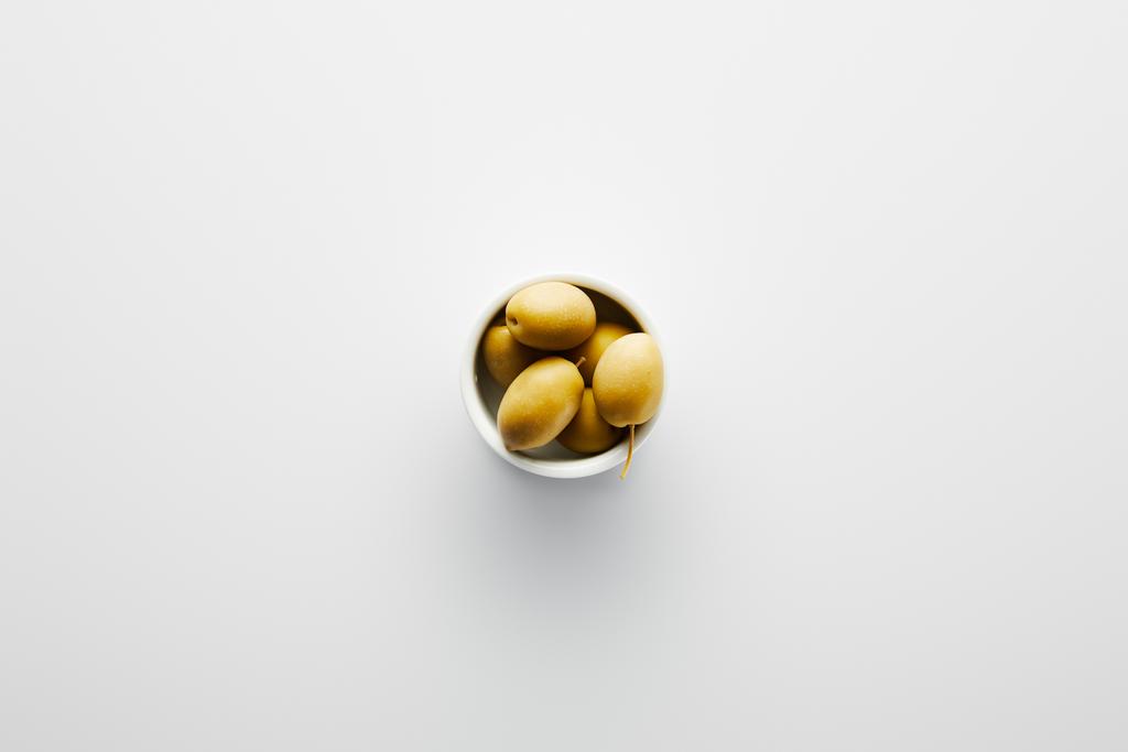 Horní pohled na mísu s olivami na bílém pozadí  - Fotografie, Obrázek