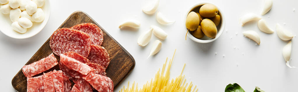 Panoramic crop of meat platter, garlic and bowls with olives and mozzarella on white background - Photo, Image