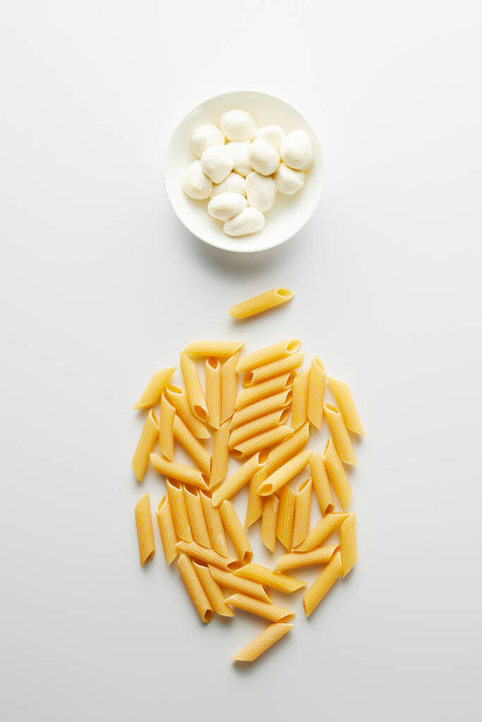Top view of pasta and bowl with mozzarella on white background  - Photo, Image