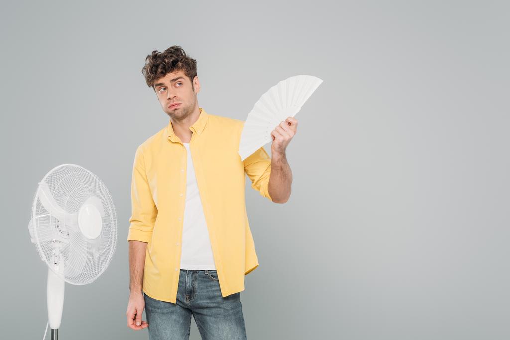 Hombre con ventiladores eléctricos y de mano mirando hacia otro lado aislado en gris
 - Foto, Imagen