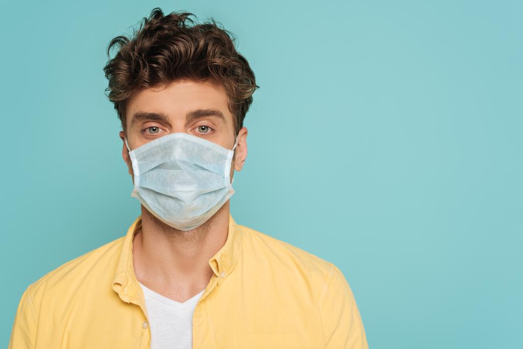 Retrato del hombre en máscara médica mirando a la cámara aislada en azul
 - Foto, imagen