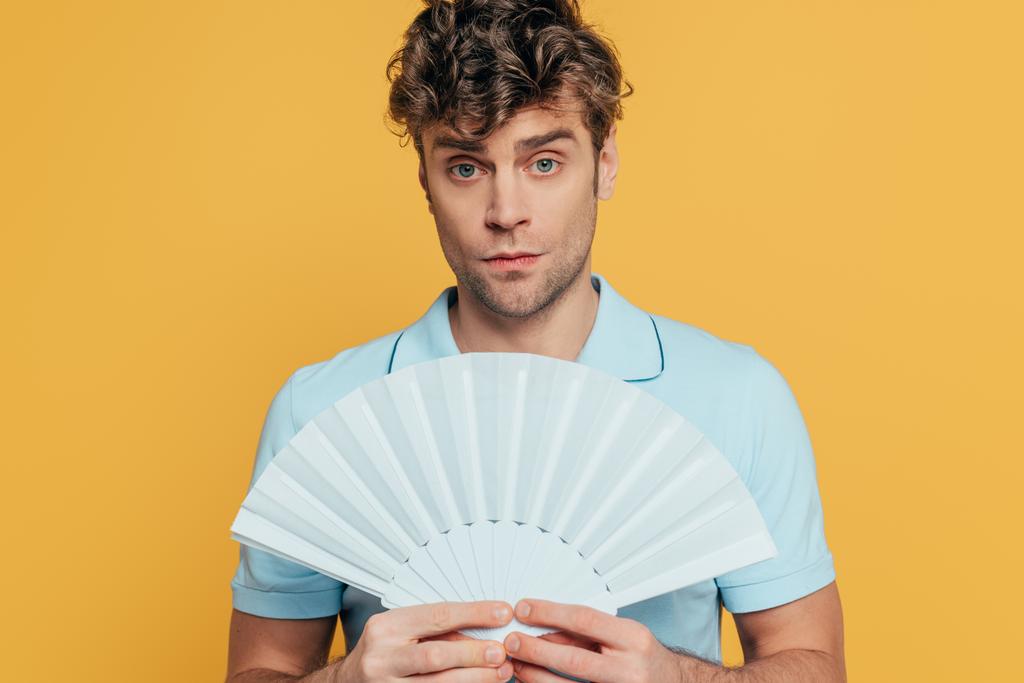 Man holding hand fan and looking at camera isolated on yellow - Photo, Image