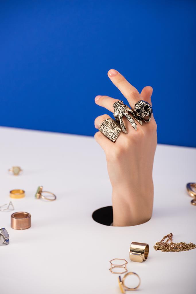 messa a fuoco selettiva della donna con braccialetto a portata di mano vicino anelli d'oro isolati su blu
 - Foto, immagini