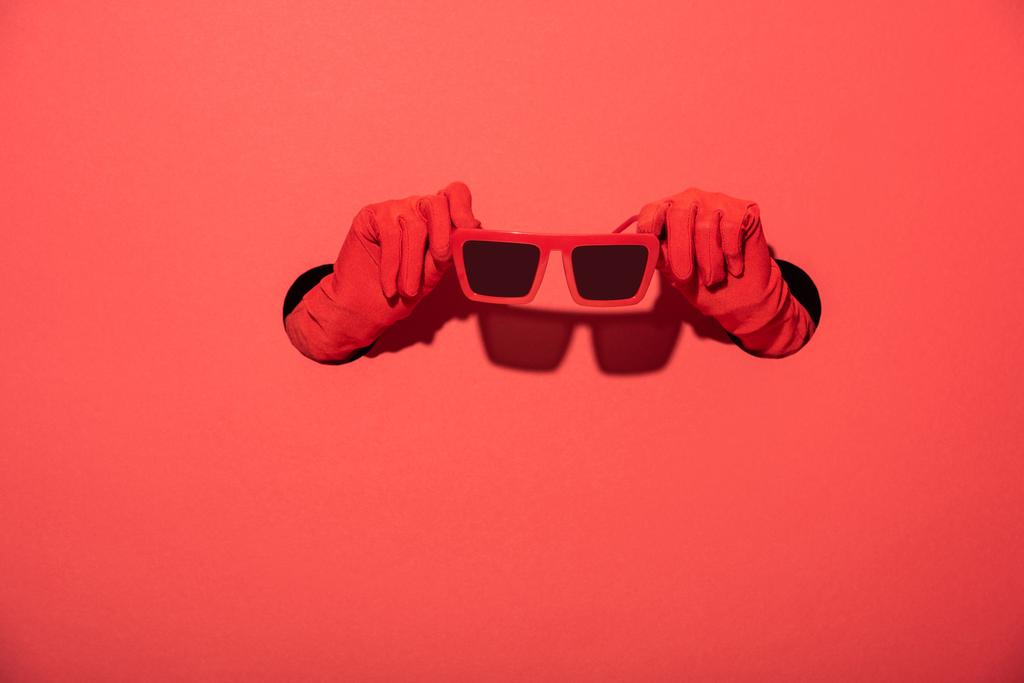 vista recortada de la mujer en guantes con gafas de sol con estilo en rojo
 - Foto, imagen