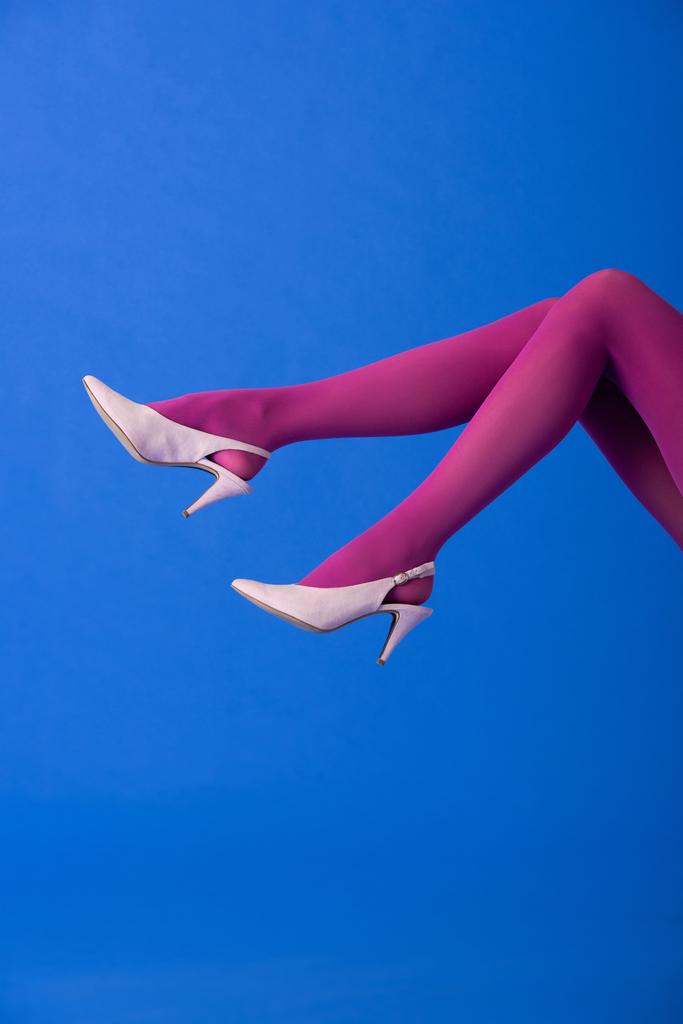 Mor taytlı ve topuklu ayakkabılı modelin mavi üzerinde duruşu. - Fotoğraf, Görsel