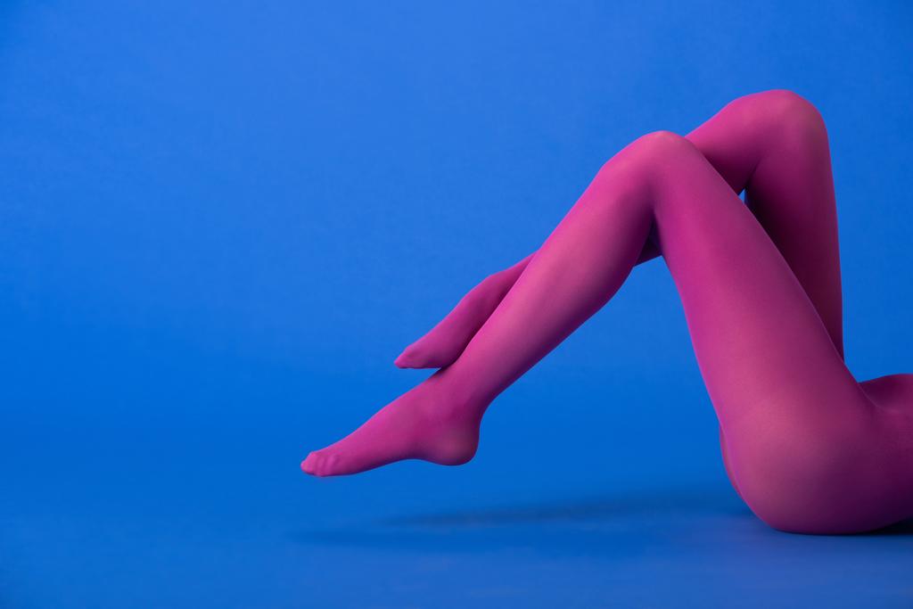 vista ritagliata della donna in collant viola colorati in posa sul blu
 - Foto, immagini