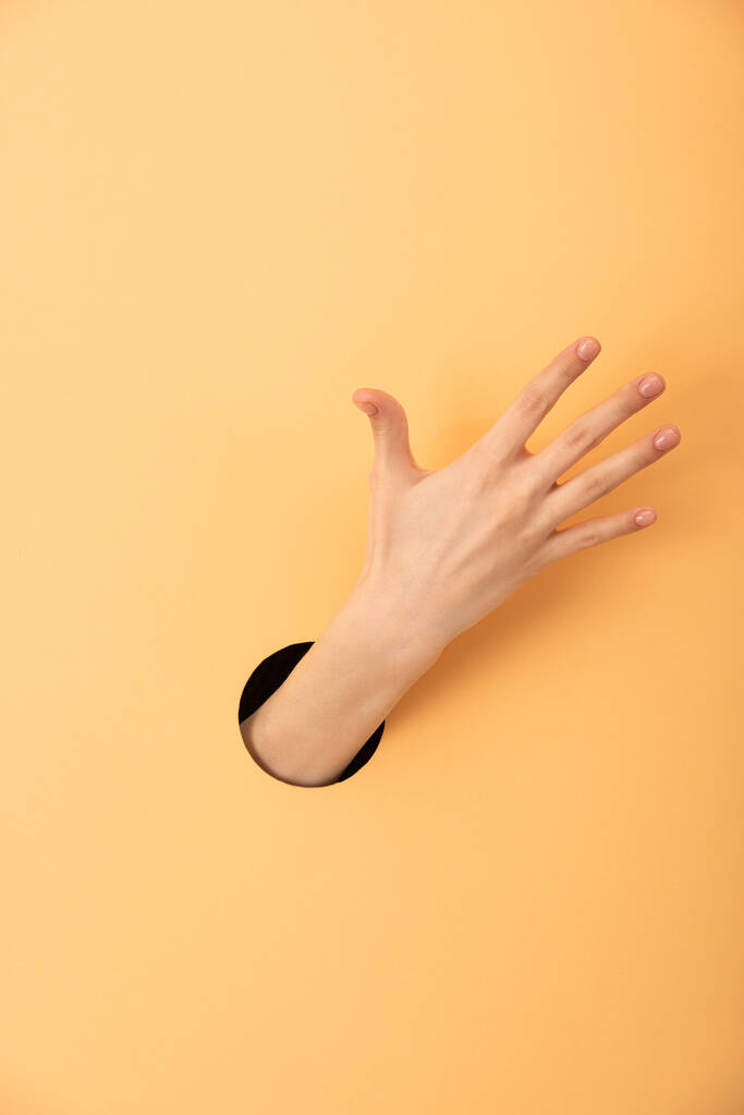 cropped view of hole with hand of woman on orange  - Photo, Image