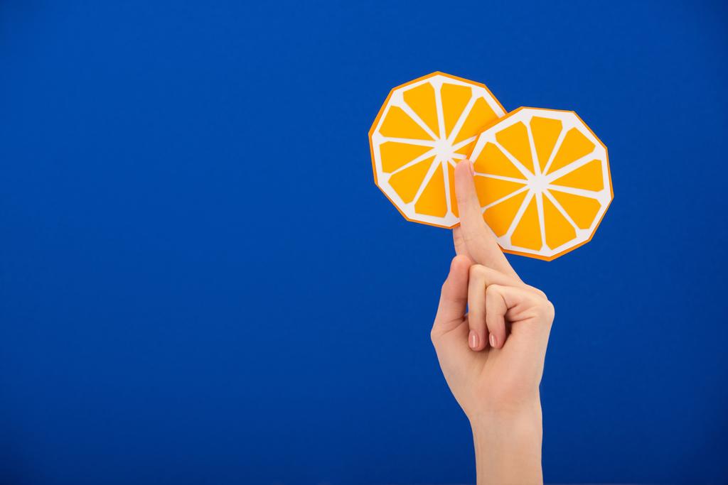 vista cortada de mulher segurando papel cortado laranja isolado em azul
 - Foto, Imagem