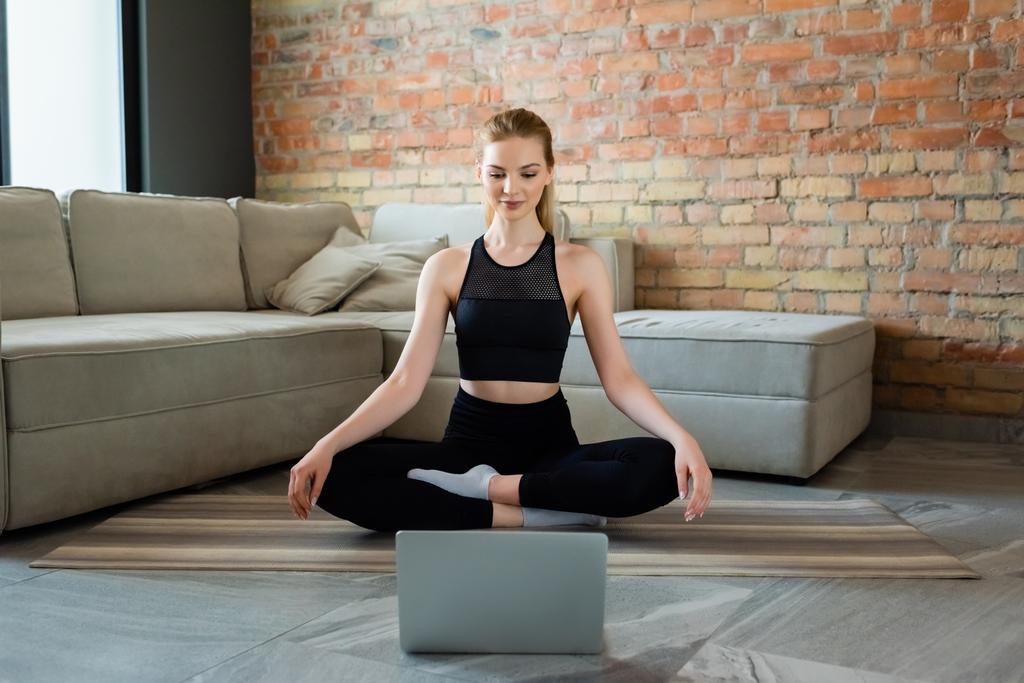 šťastný sportovkyně ponožky a jóga póza sledování online jóga cvičení na notebooku - Fotografie, Obrázek