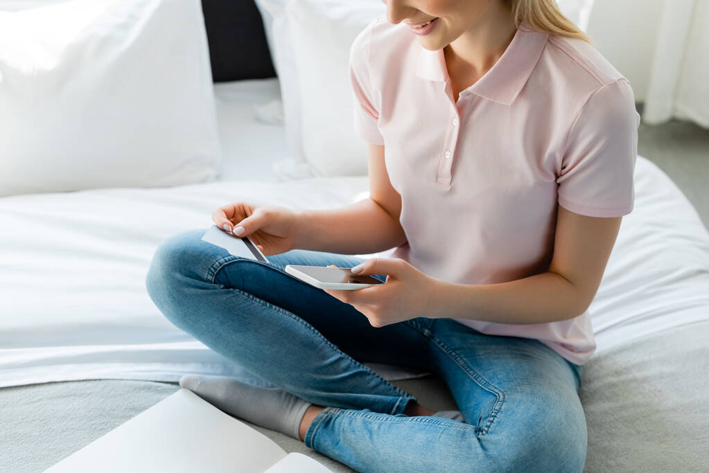 vista ritagliata di donna felice con smartphone e carte di credito in camera da letto
  - Foto, immagini