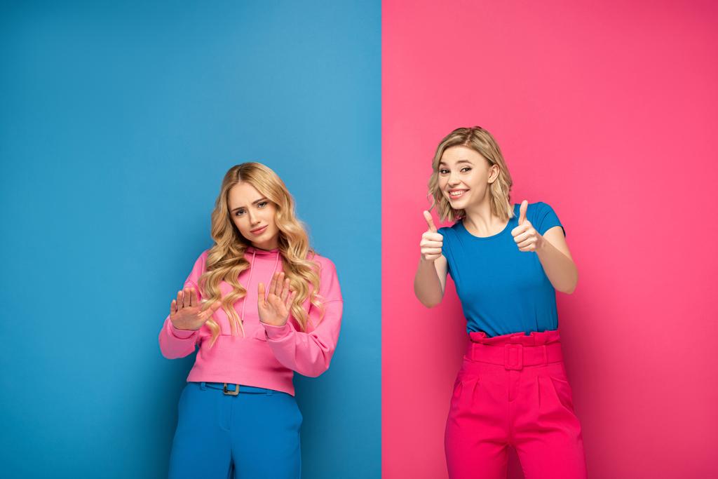Blondýny sestry ukazující odpad a palce nahoru značky na růžovém a modrém pozadí - Fotografie, Obrázek