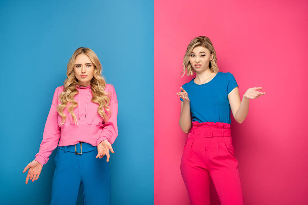 Confundidas hermanas rubias mirando a la cámara sobre fondo rosa y azul
 - Foto, imagen
