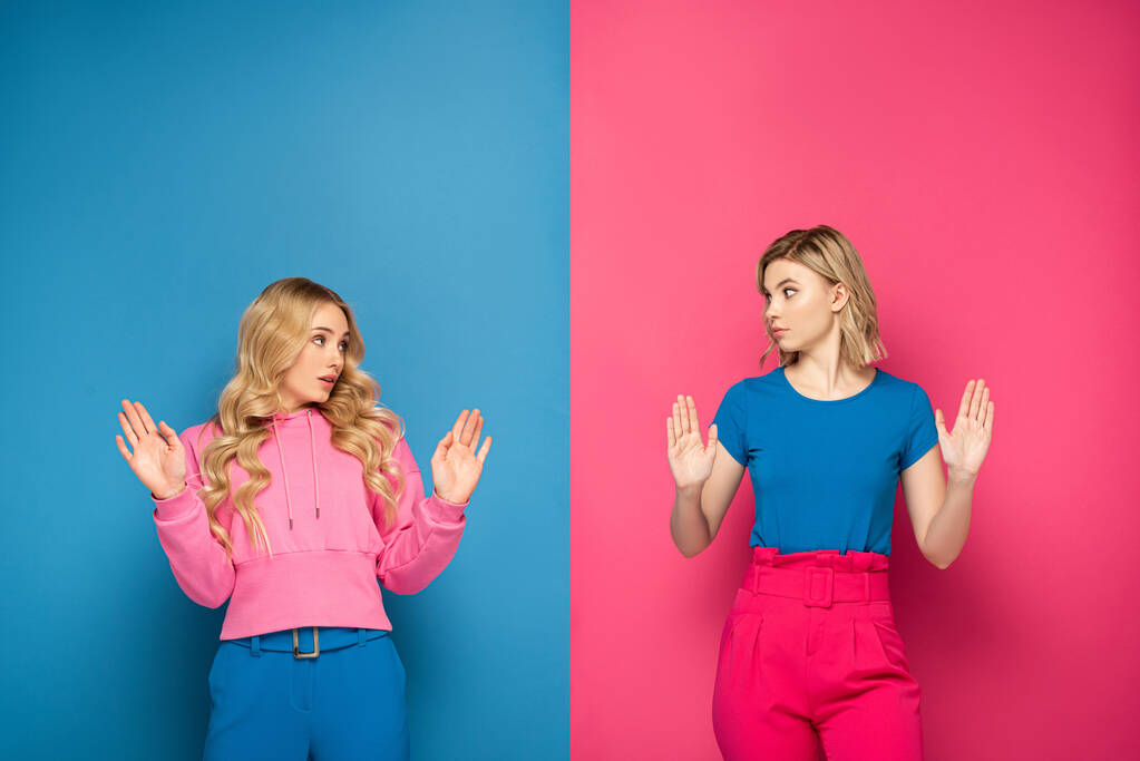 Μπερδεμένη ξανθιά κορίτσια δείχνουν στάση χειρονομία σε ροζ και μπλε φόντο - Φωτογραφία, εικόνα