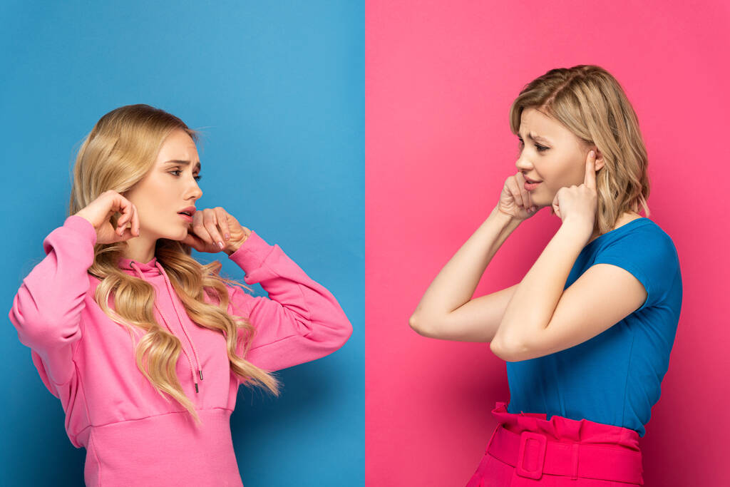 Sceptyczne blondynki zakrywające uszy patrząc na siebie na różowym i niebieskim tle - Zdjęcie, obraz