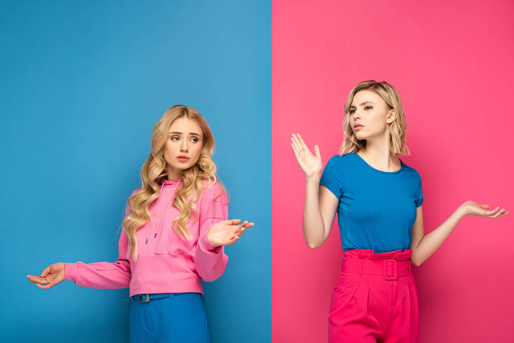 Verwirrte blonde Mädchen zeigen Achselzucken-Geste auf rosa und blauem Hintergrund - Foto, Bild