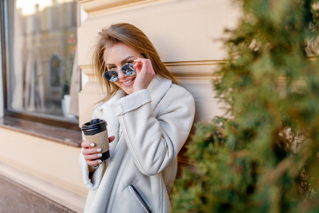 Portrét mladé módní ženy s donáškou kávy, v blízkosti budovy města. - Fotografie, Obrázek