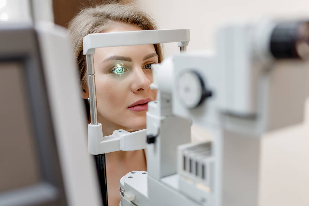 Молода красива жінка з світлим волоссям діагностується з тиском очей на спеціальне офтальмологічне обладнання
. - Фото, зображення
