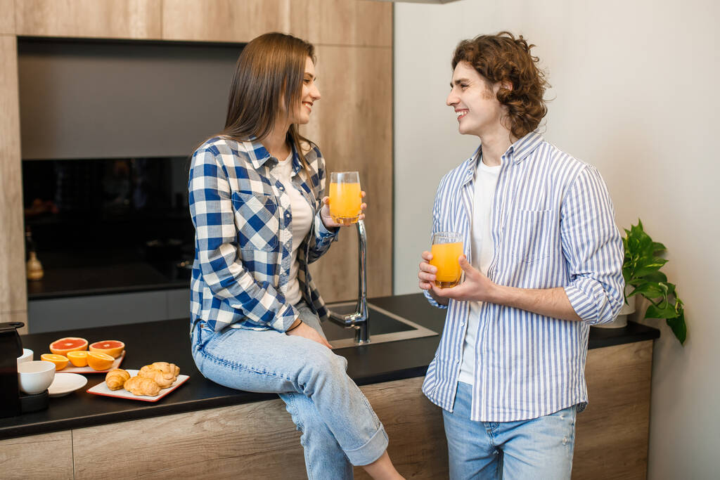 Retrato de gente feliz bebiendo jugo de naranja fresco en la cocina casera
. - Foto, imagen