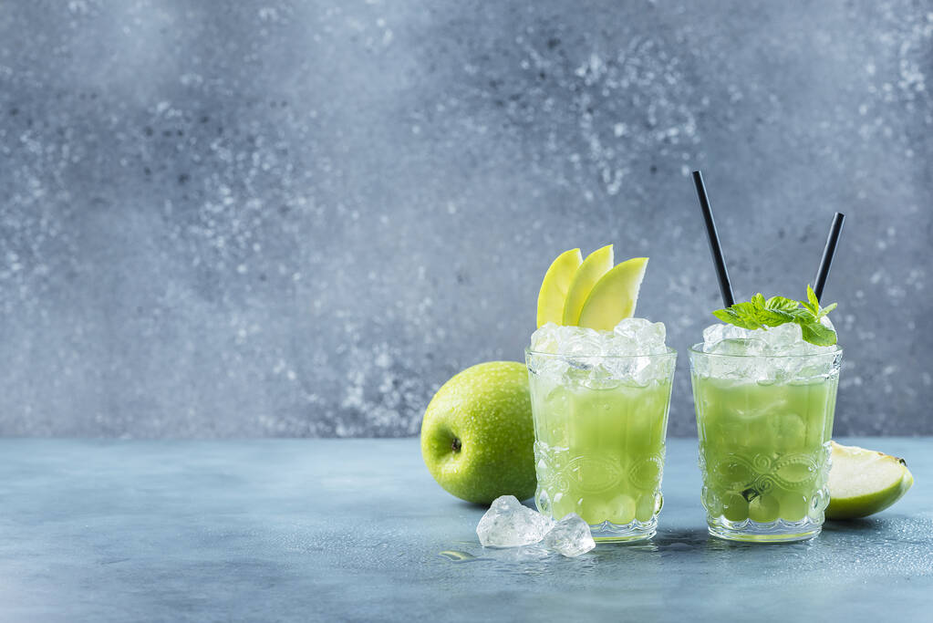 Groene cocktail met ijs en munt. Bar concept. Apple mojito met munt en ijs op de blauwe achtergrond, selectieve focus afbeelding - Foto, afbeelding