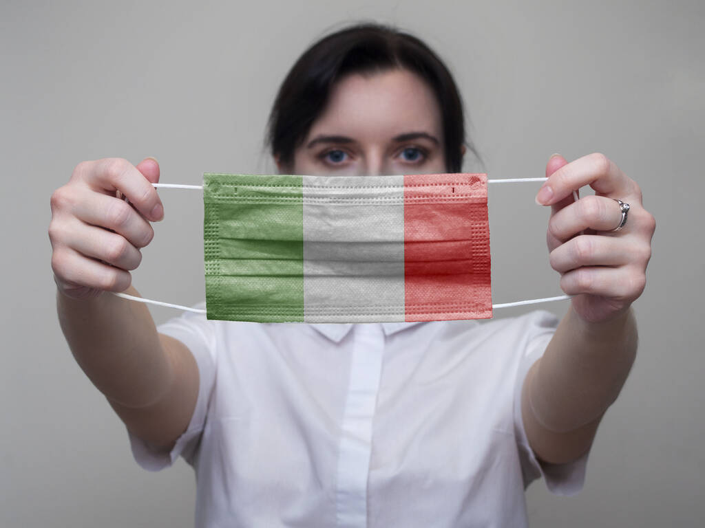 La donna regge una maschera medica con l'immagine della bandiera italiana. Coronavirus COVID-19
 - Foto, immagini