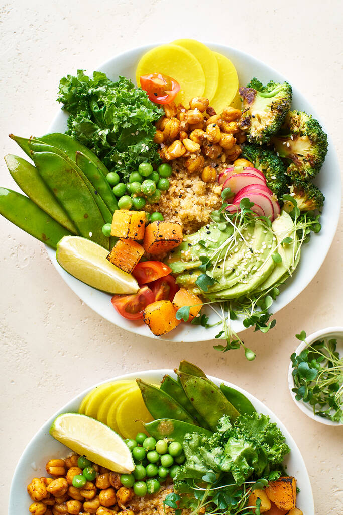 Healthy vegetarian lunch bowls with avocado and chickpeas with quinoa and vegetables garnished with microgreens and nut dressing  on stone background - Photo, Image