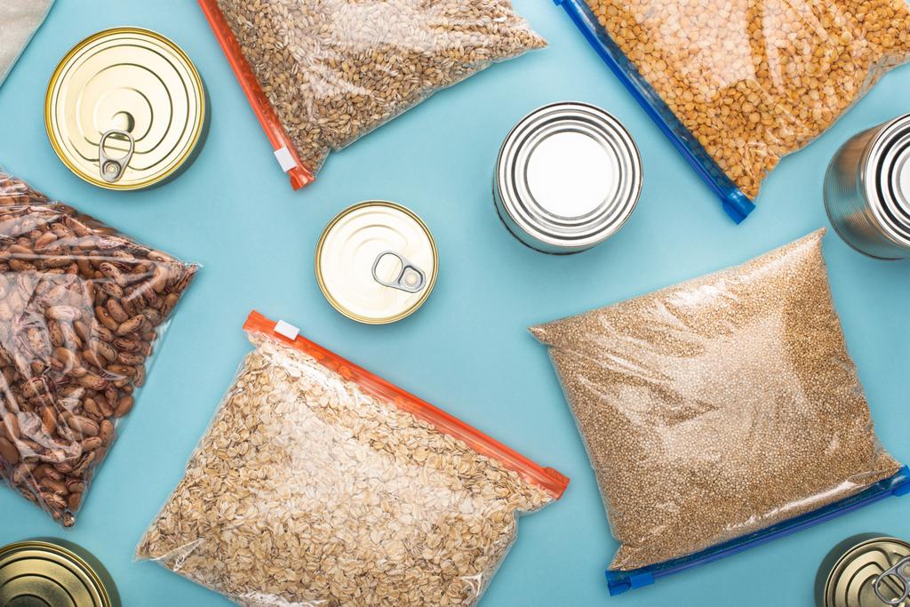 верхний вид банки и крупы в молнии мешки на синем фоне, концепция пожертвования продуктов питания
 - Фото, изображение
