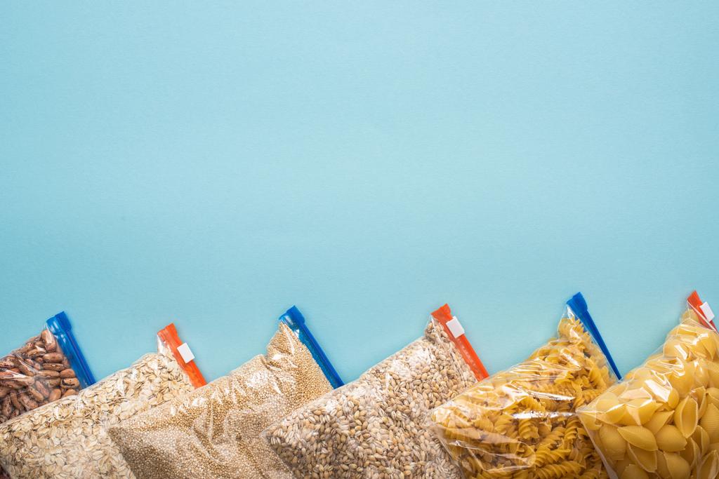 верхний вид пасты, бобы и крупы в молнии мешки на голубом фоне, концепция пожертвования продуктов питания
 - Фото, изображение