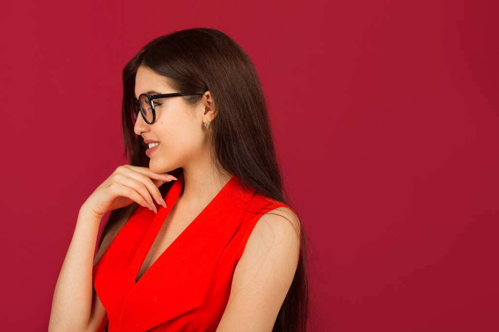  beautiful young woman with makeup in a red suit on a red background - Photo, Image