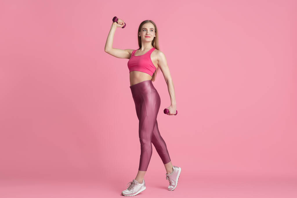 Όμορφη νεαρή αθλήτρια προπονείται σε ροζ φόντο στούντιο, μονόχρωμο πορτρέτο - Φωτογραφία, εικόνα