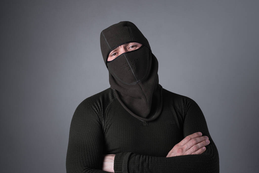 Kar maskeli bir adam, özel kuvvetler konsepti olarak, tehditkar bir bakışla duruyor, ellerini göğsüne yapıştırıyor. - Fotoğraf, Görsel