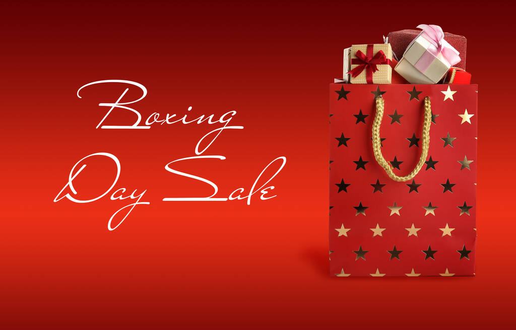 Ausverkauf am zweiten Weihnachtsfeiertag. Einkaufstasche mit Geschenken auf rotem Hintergrund - Foto, Bild