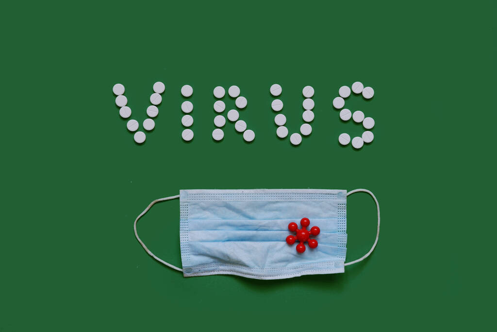 VIRUS επιγραφή από λευκά χάπια σε μαύρο φόντο με ιατρική μάσκα - Φωτογραφία, εικόνα