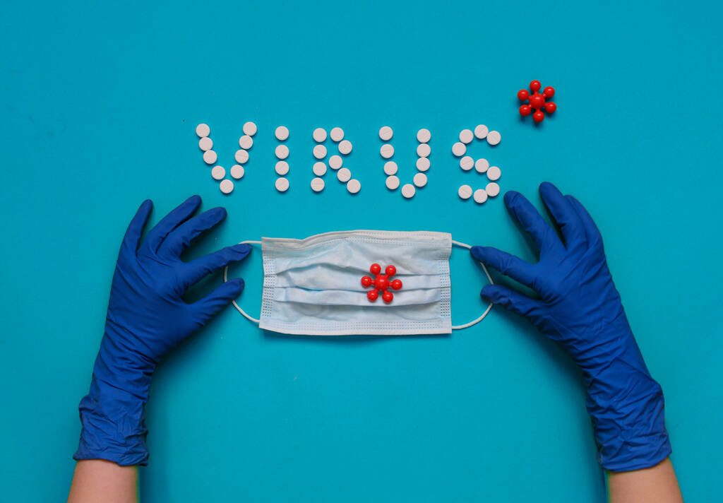 白い丸薬からのウイルスの碑文、保護手袋の手は医療マスクを保持 - 写真・画像