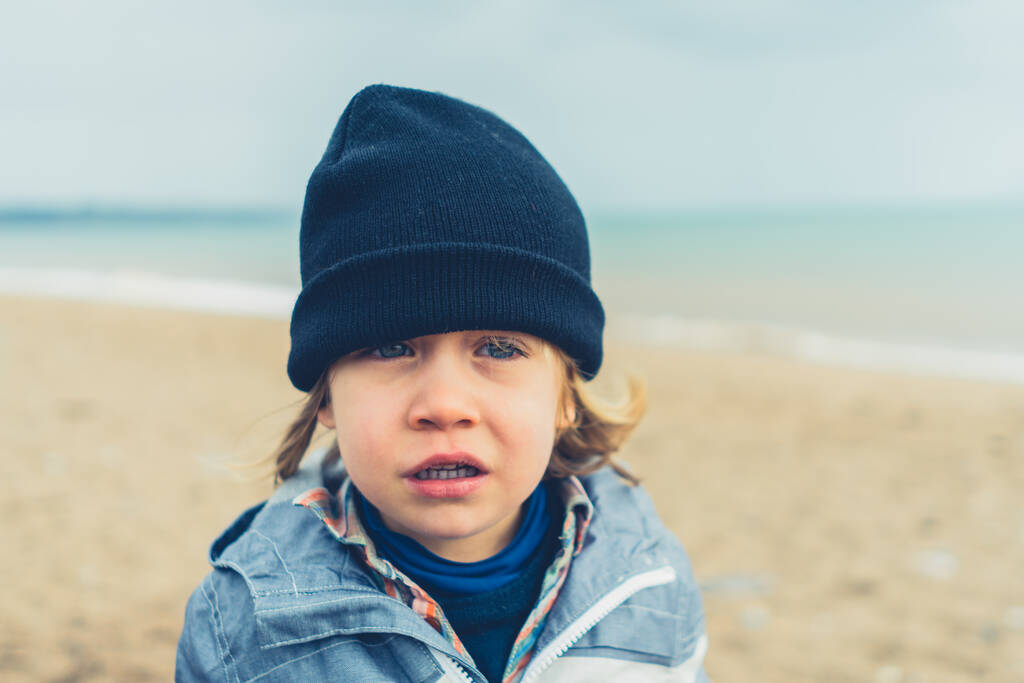 Un bambino in età prescolare è in piedi sulla spiaggia in una giornata fredda
 - Foto, immagini
