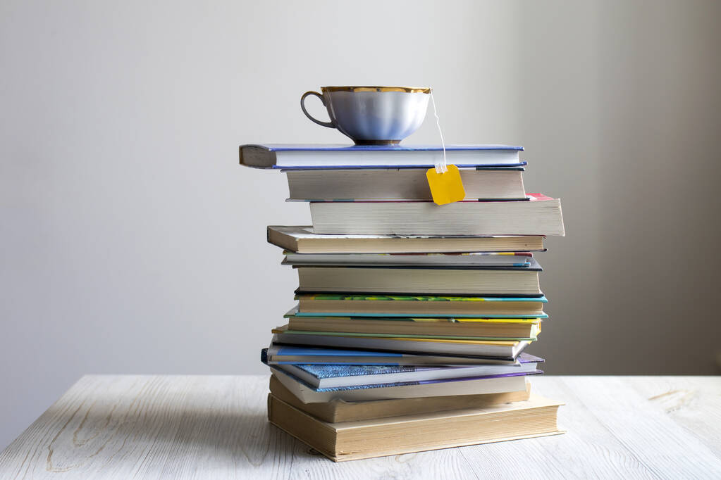 Un montón de libros con una taza de té con una bolsa encima. Aprendizaje en línea de Coronovirus
 - Foto, imagen