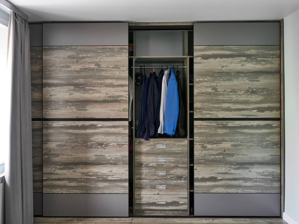 Modern wardrobe with open sliding doors and drawers in room. - Photo, Image