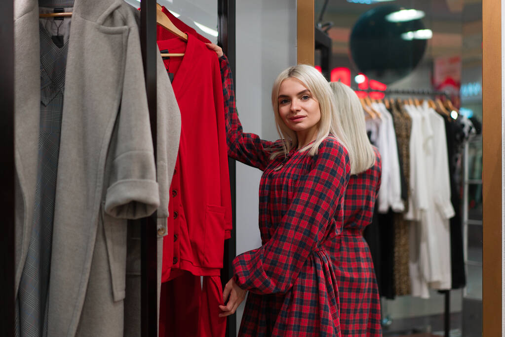 Jedna kavkazská žena v módním butiku si vybere šaty. Profesionální stylista pomáhá zákazníkům vybírat oblečení. Sezóna dovolená nakupování slevy prodej Evropská dívka chůze nákupní centrum. Životní styl  - Fotografie, Obrázek