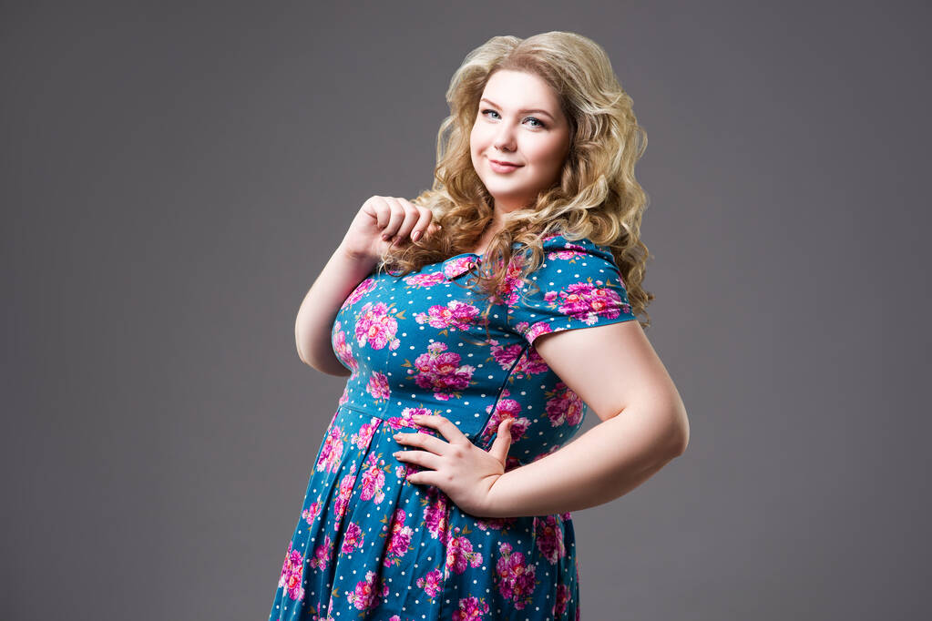 Plus velikost módní model v květinových šatech, tlustá žena na šedém pozadí, tělo pozitivní koncept - Fotografie, Obrázek